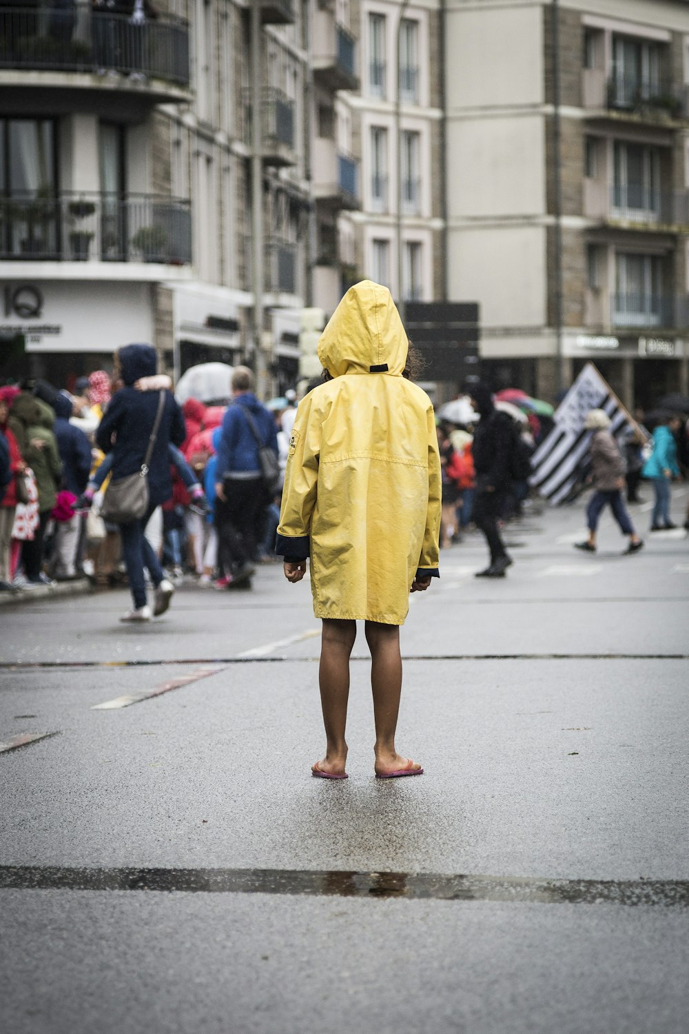 femme en manteau jaune marchant dans la rue pendant la journée