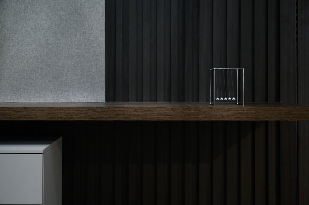 clear drinking glass on brown wooden shelf