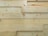 Several overlapping wooden planks with visible grain patterns and knots. The wood has a smooth finish and light natural color.