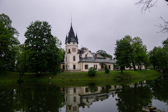 white and brown concrete building near green trees and body of water during daytime in Olszanica, Podkarpackie Voivodeship Poland