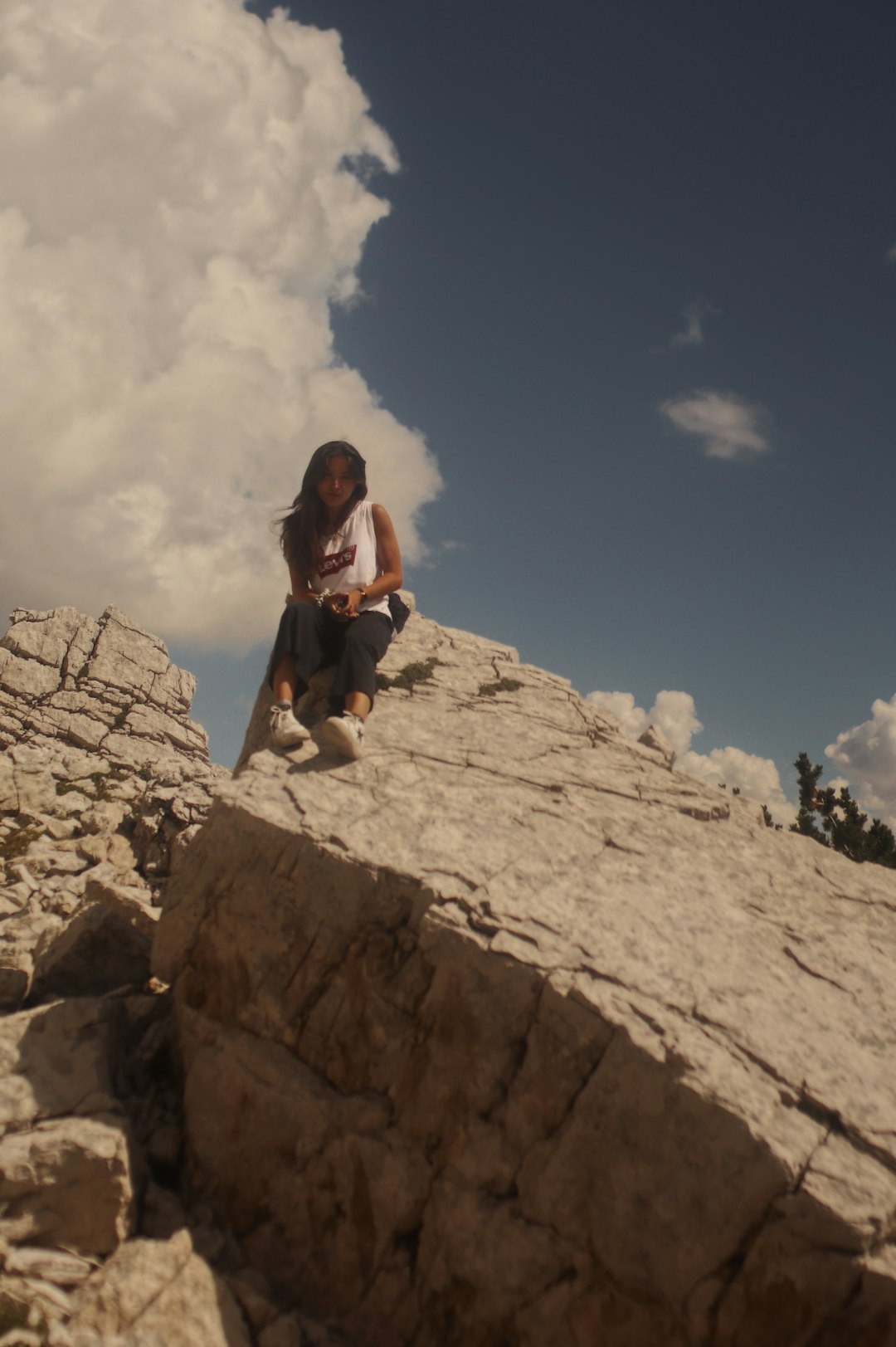 woman in black shirt sitting on rock formation under blue sky during daytime