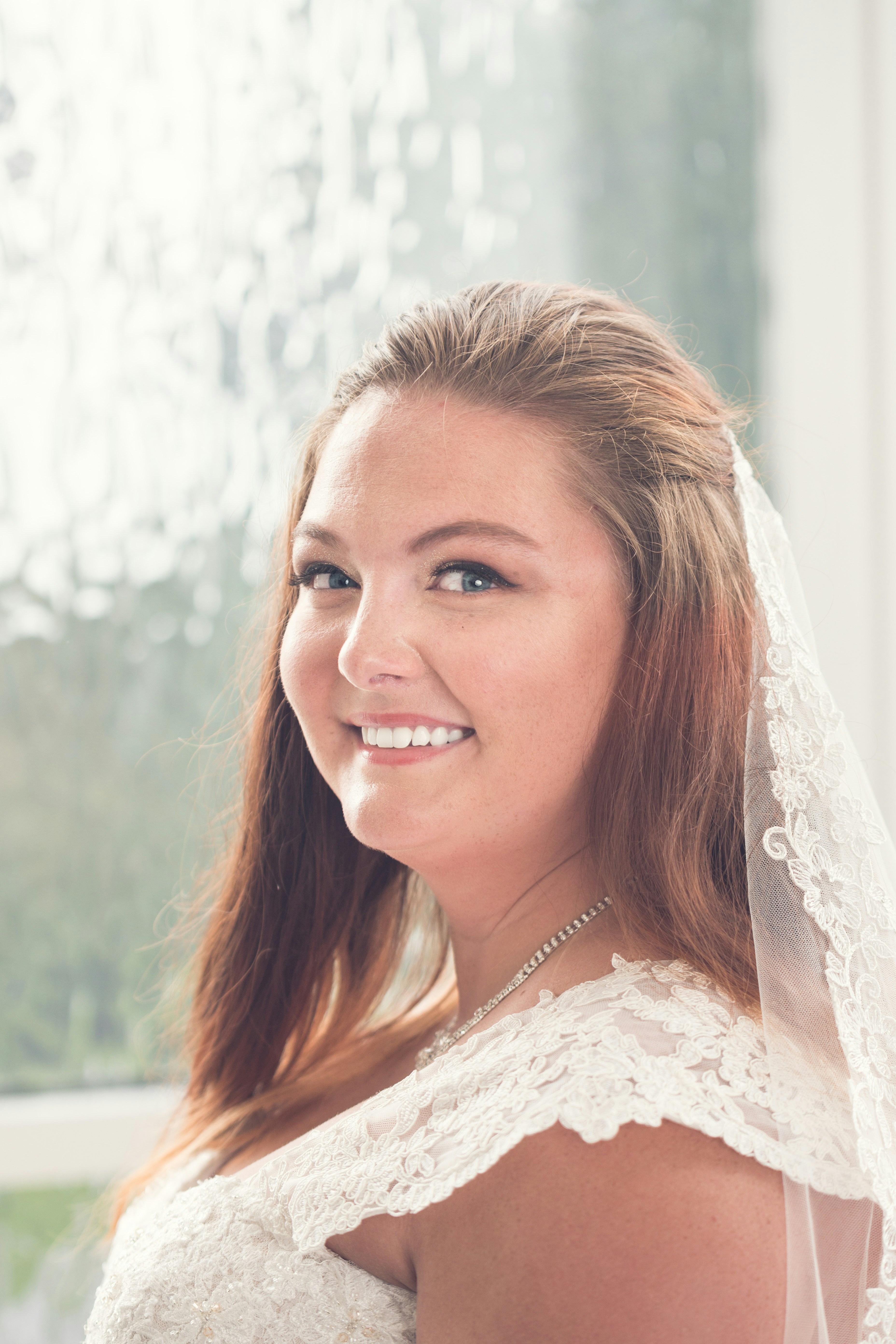 woman in white floral lace top smiling