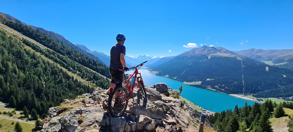 man in blue shirt and black shorts standing on rocky mountain during daytime