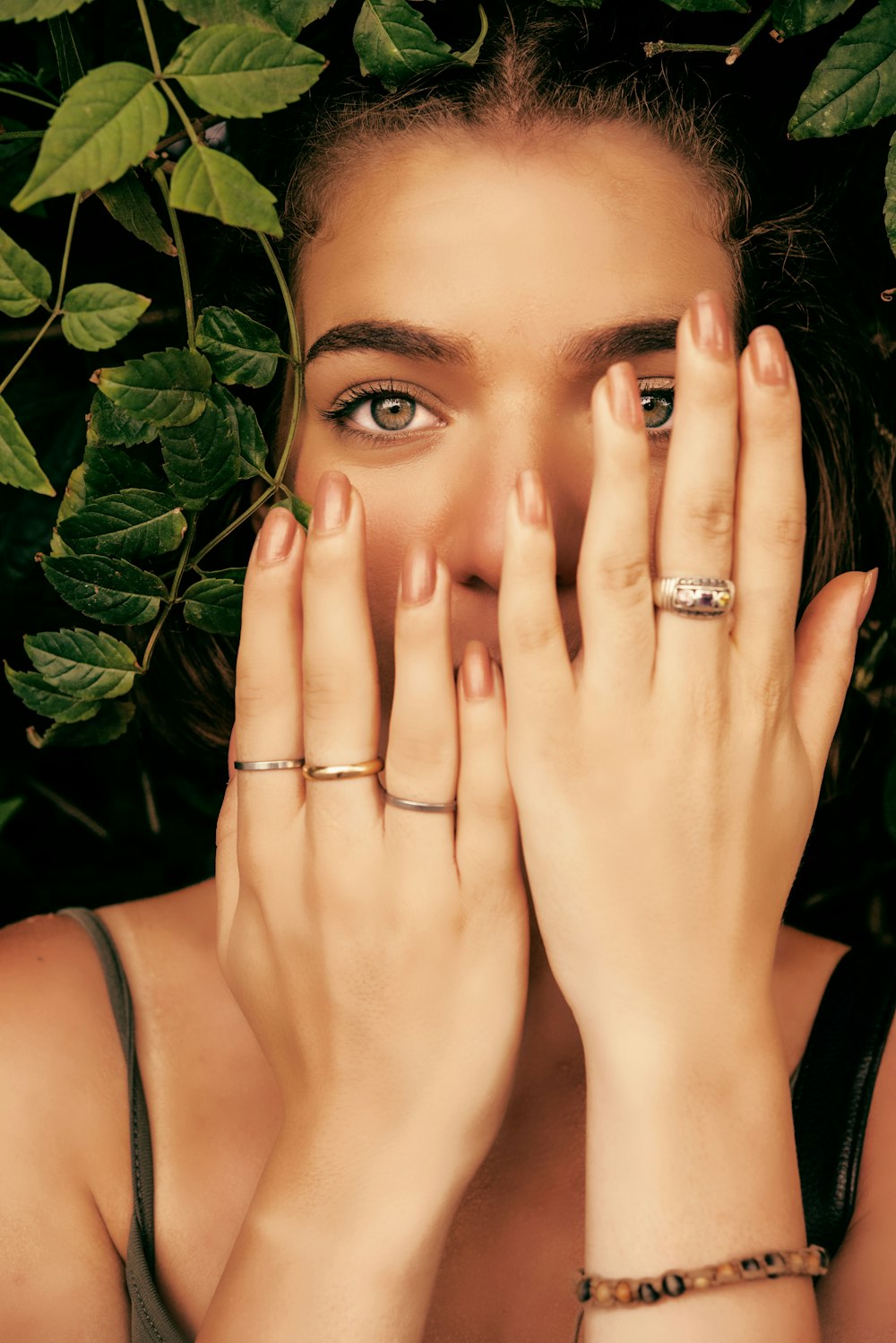 woman in black tank top covering her face with her hands