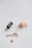 A dropper bottle of skincare oil is placed next to a rose quartz facial roller and several rose quartz stones, including a heart-shaped one.
