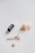 A dropper bottle of skincare oil is placed next to a rose quartz facial roller and several rose quartz stones, including a heart-shaped one.