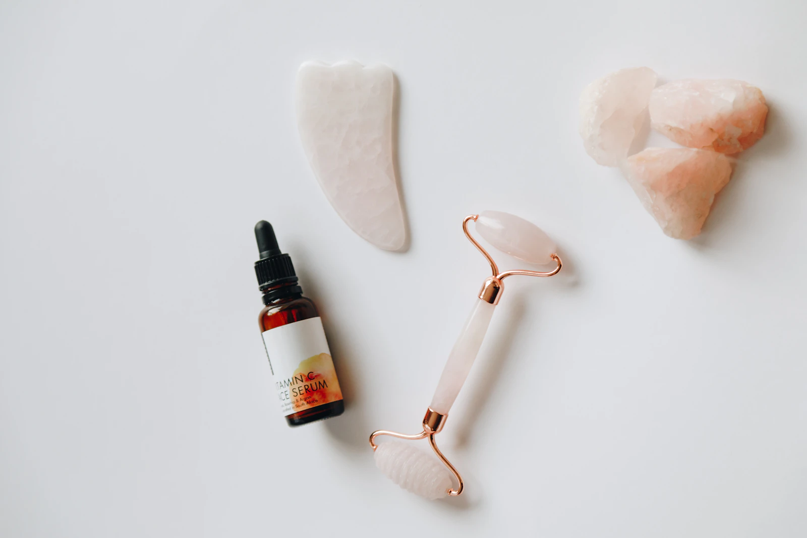 Flacon de sérum visage avec pipette, rouleau et gua sha en quartz sur fond clair