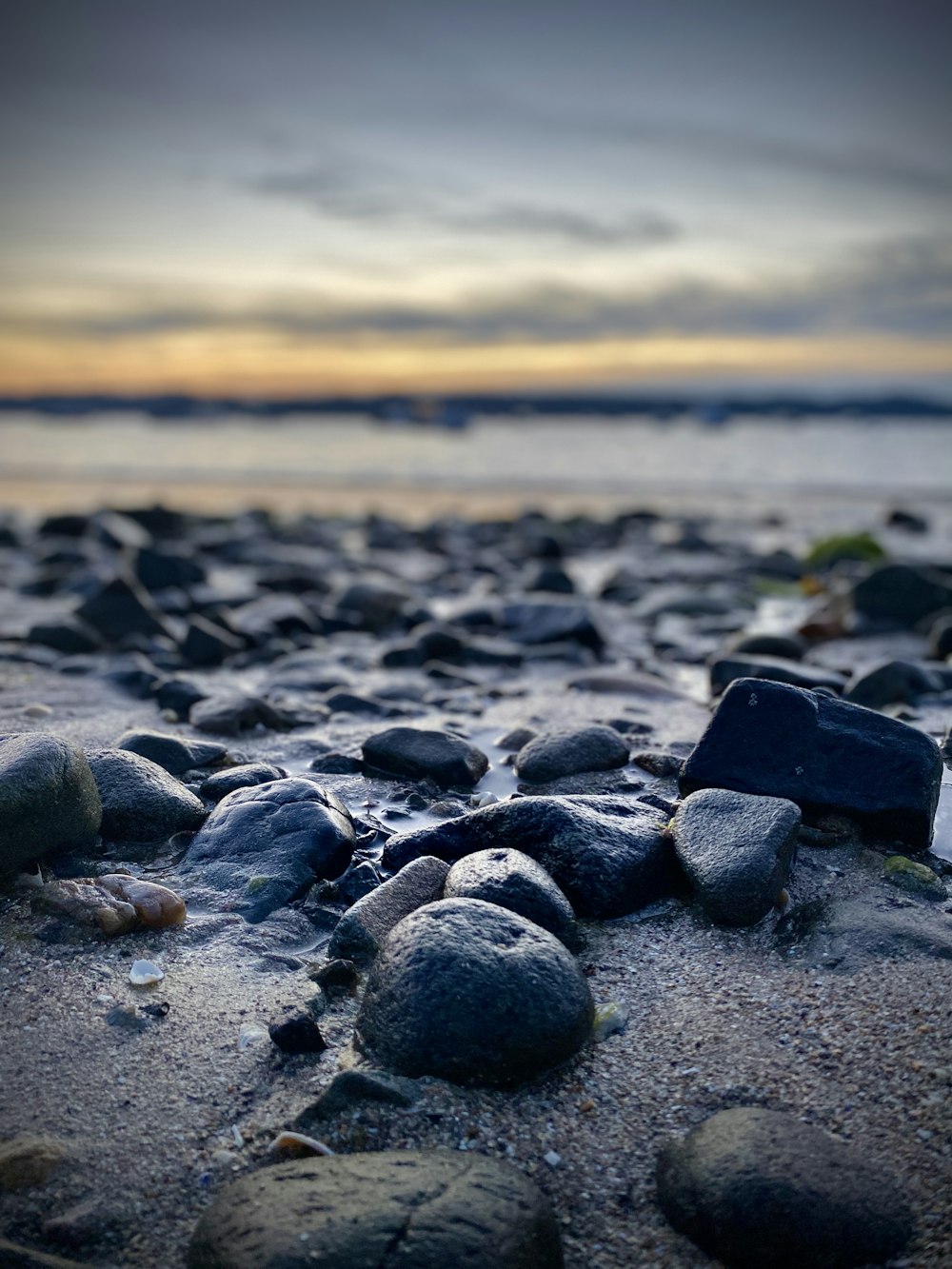 black stones on beach shore during sunset
