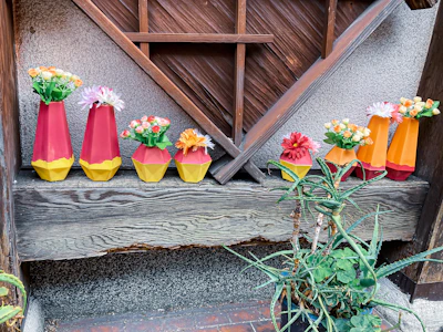 Colorful 3D printed decorative vases arranged on a wooden shelf.