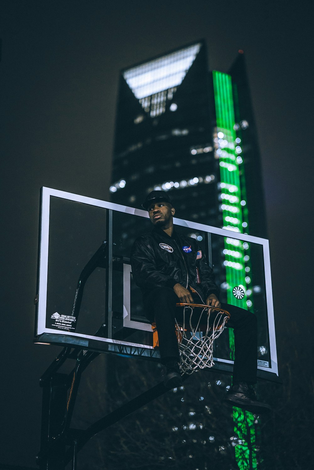 man in black jacket sitting on basketball hoop