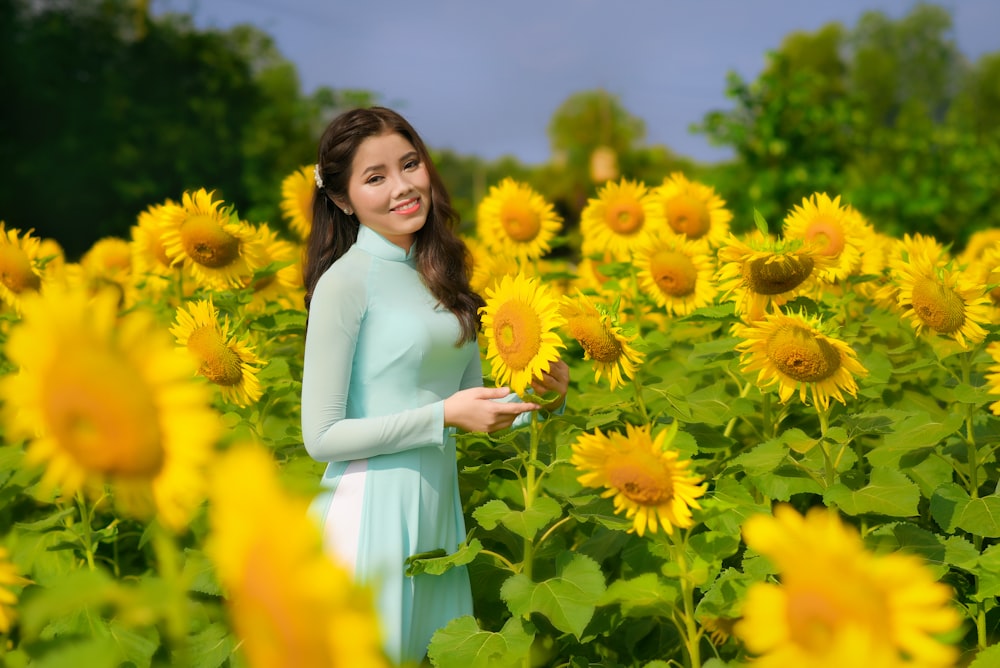 mulher no vestido branco que está no campo da flor amarela durante o dia