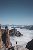 A solo traveler standing on a rocky outcrop, looking over a vast mountain range.