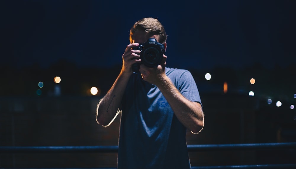 man in black t-shirt holding black dslr camera