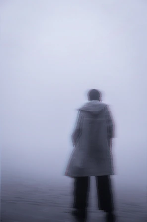 A blurred photograph of an unidentifiable figure caught in the fog on a deserted street.