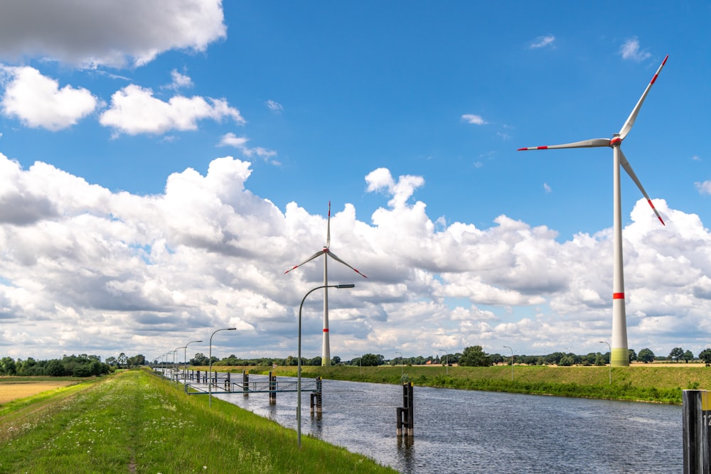 white wind turbines on green grass field under blue and white cloudy sky during daytime