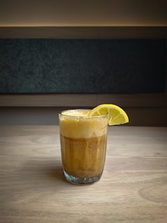 clear drinking glass with yellow liquid on brown wooden table