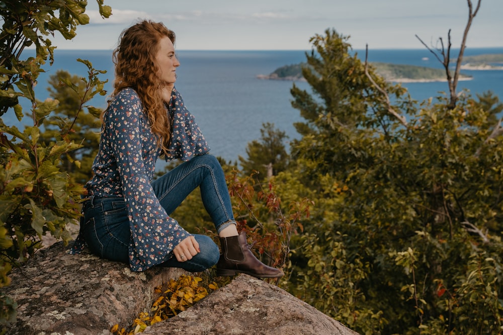 woman in blue and white long sleeve shirt and blue denim jeans sitting on rock near near near near near