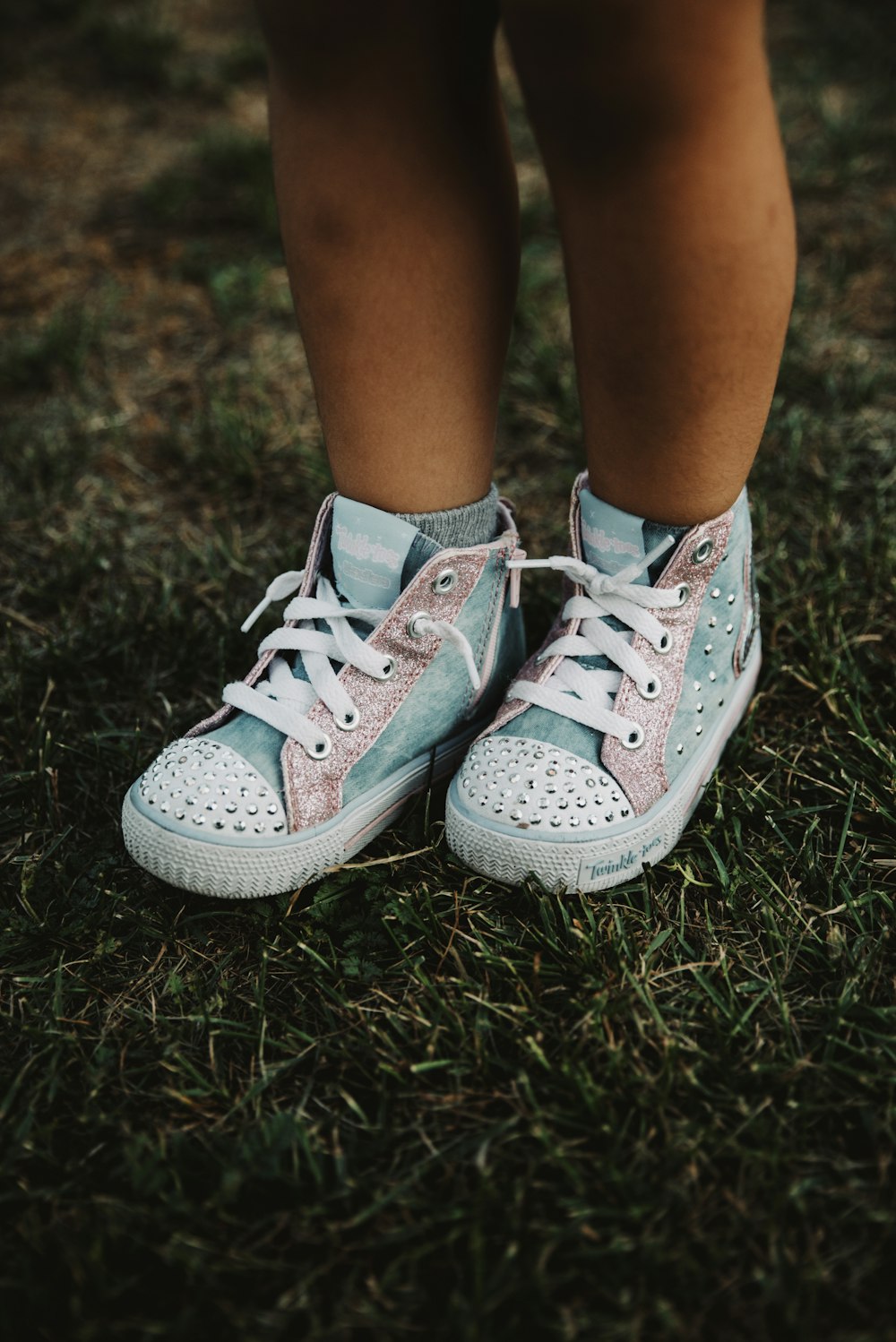 person wearing white and gray sneakers standing on green grass during daytime