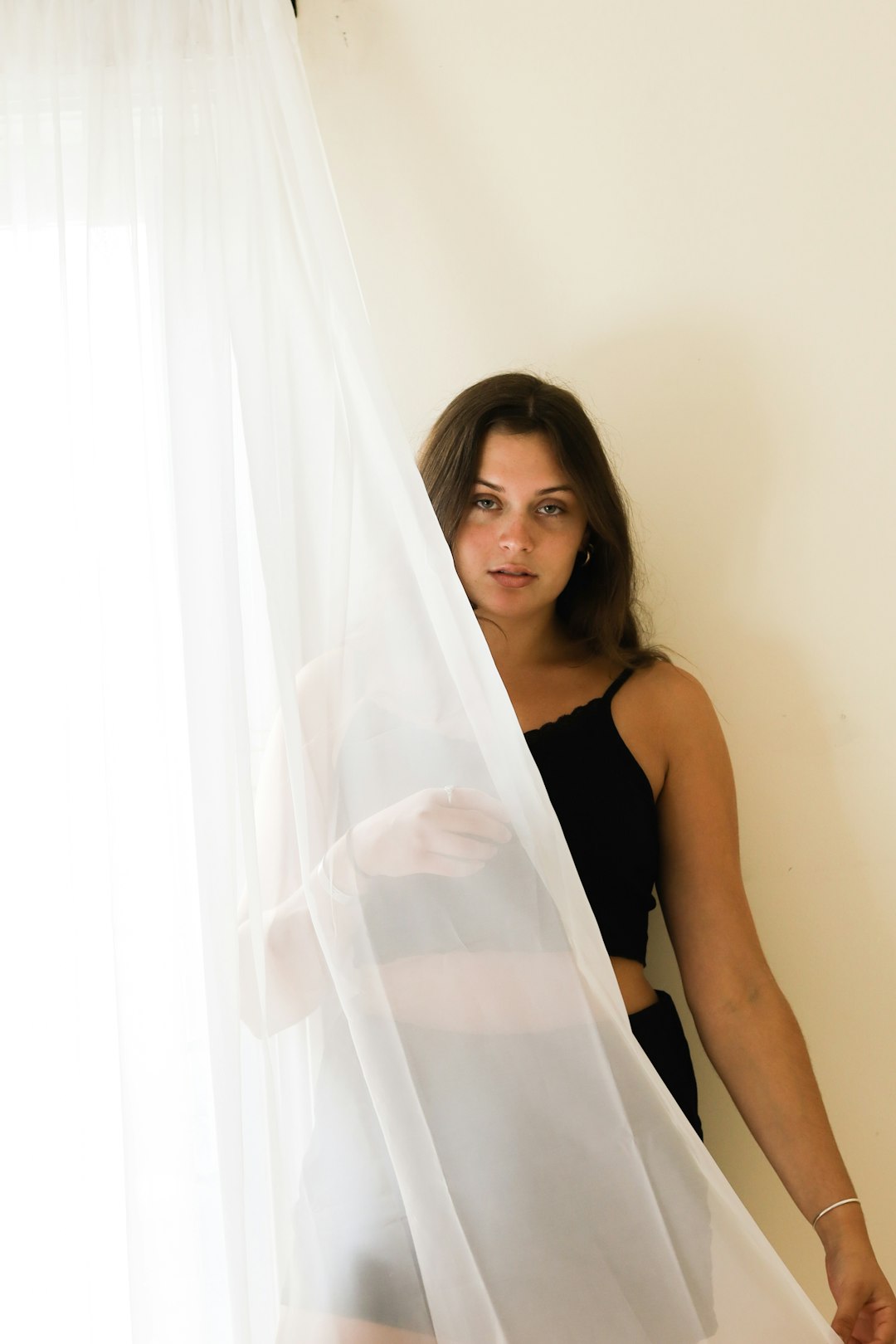 woman in black tank top holding white sheer textile