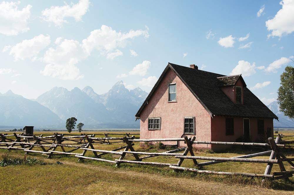 maison en bois marron et blanc sur le champ d’herbe verte sous les nuages blancs pendant la journée