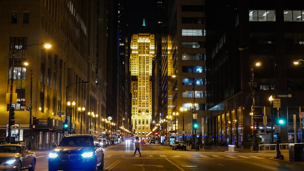 cars on road in between high rise buildings during night time