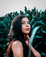 woman in black tank top standing beside green plant