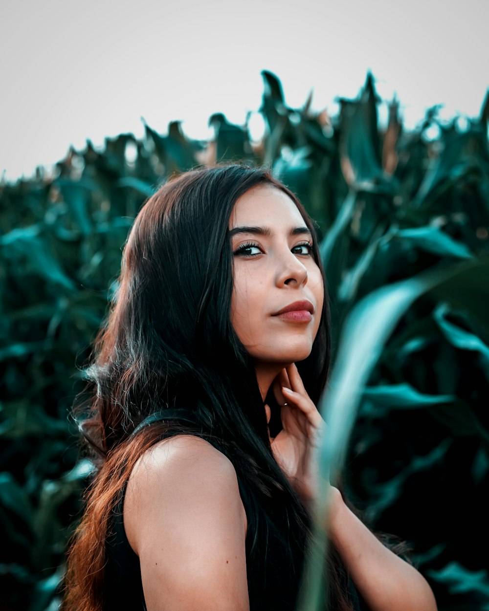 woman in black tank top standing beside green plant