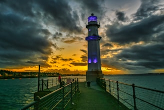 black and white lighthouse near body of water during sunset