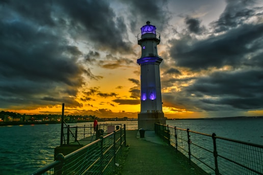 black and white lighthouse near body of water during sunset