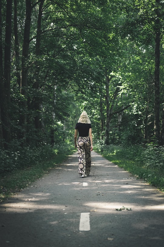 woman in brown and black dress riding bicycle on gray asphalt road during daytime in Vä Sweden