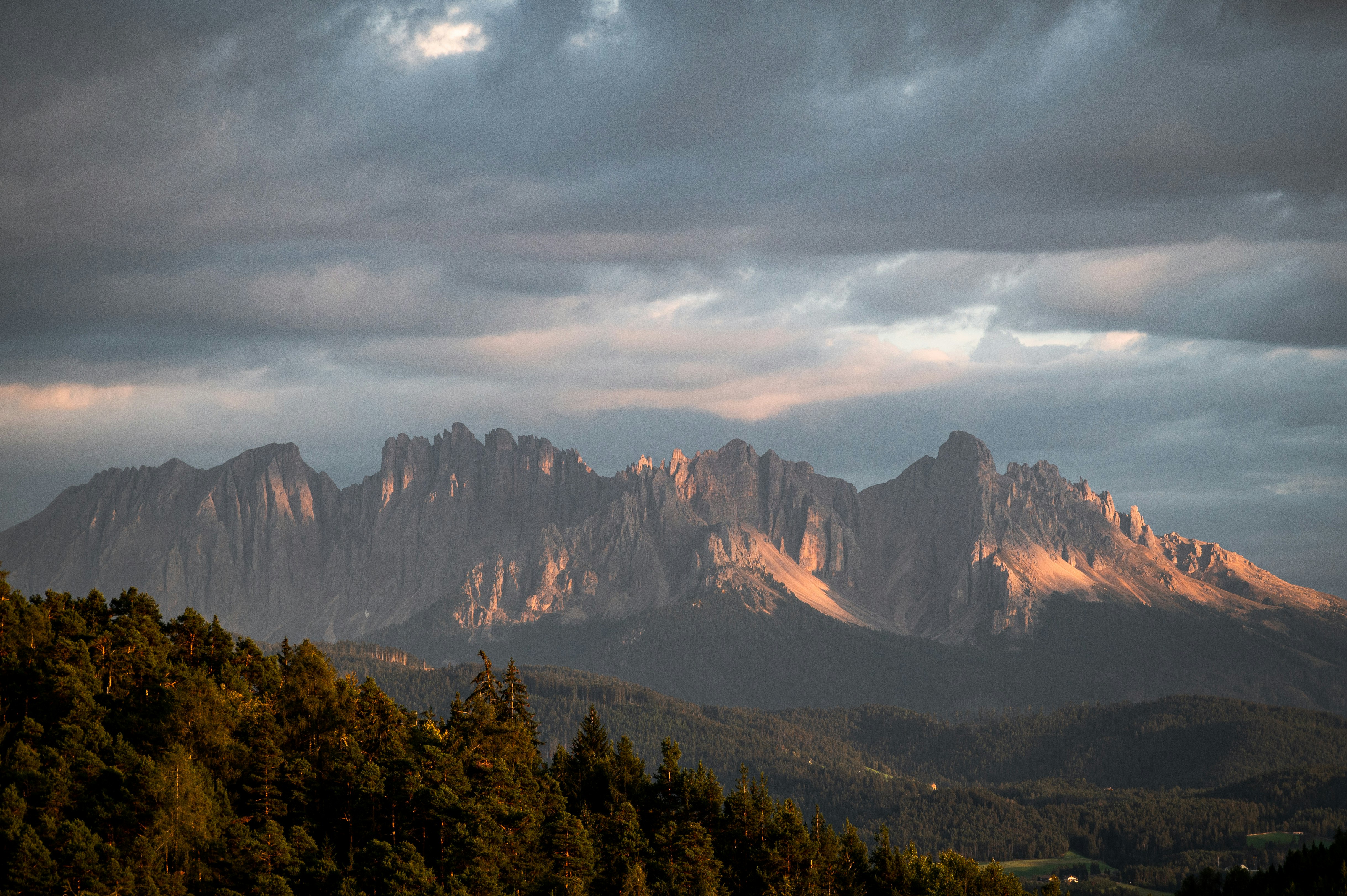 green trees and mountains under white clouds