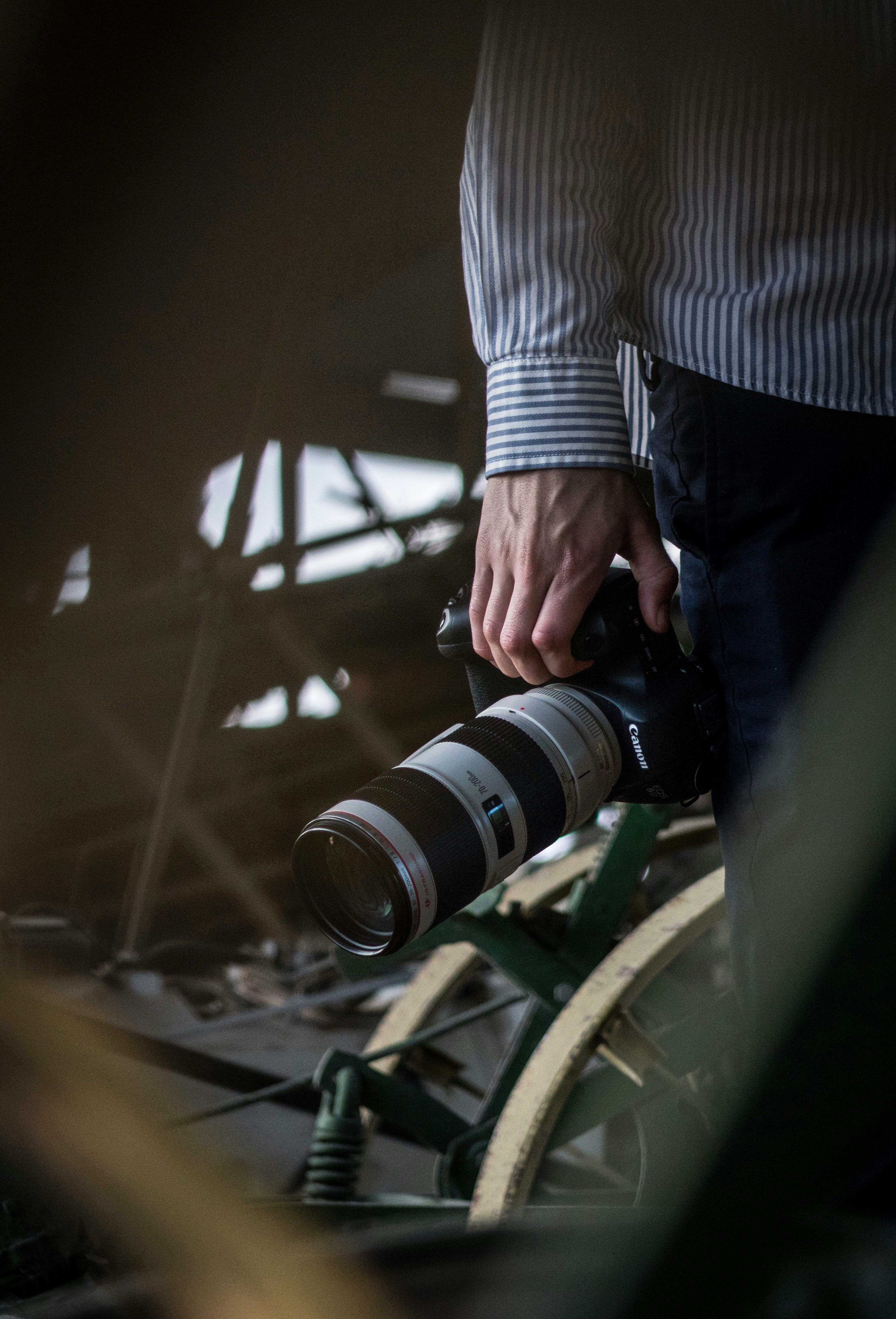 personne en chemise rayée blanche et noire tenant un appareil photo