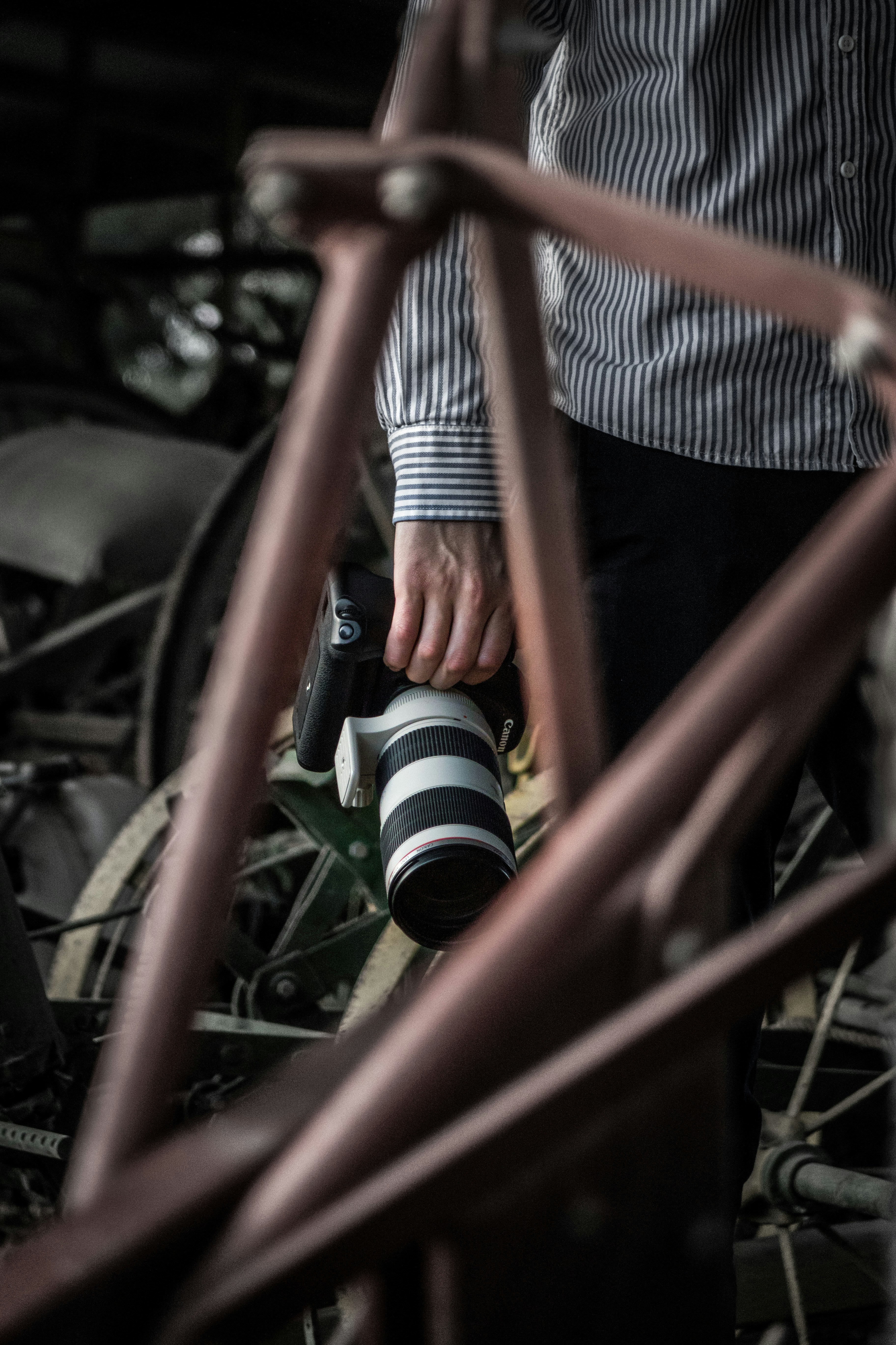 person in white and red striped shirt and black pants holding black and white dslr camera