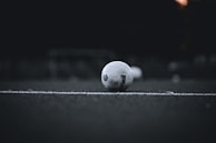 A minimalist black and white photo of a soccer ball resting on freshly cut grass at sunrise.