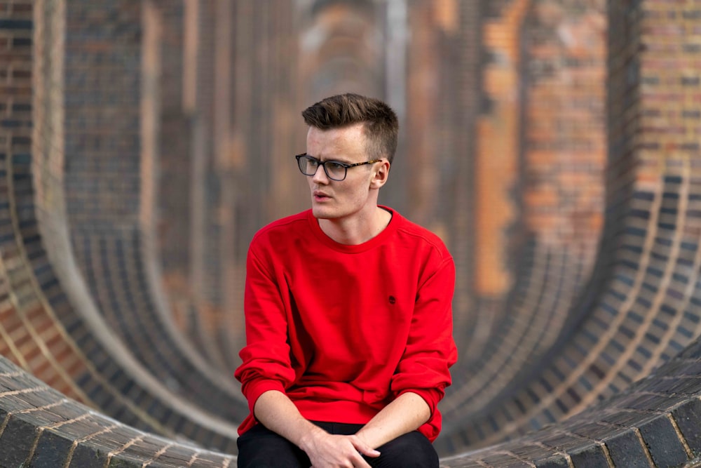 man in red sweater sitting on the ground