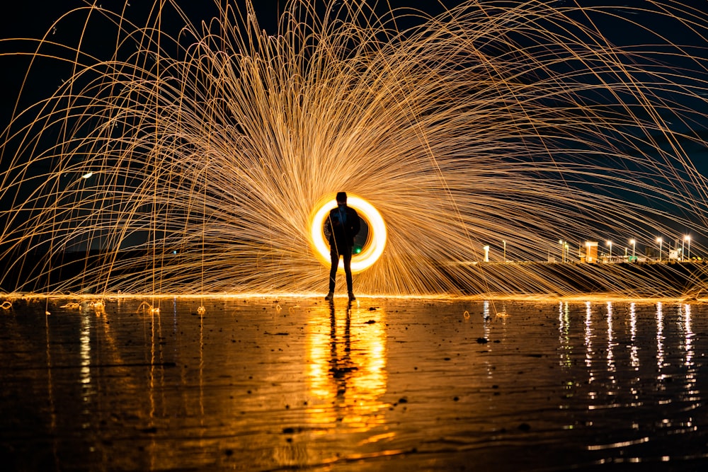 person standing on dock with fireworks display during night time