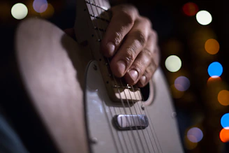 A close-up photo capturing Yasheita’s fingers on guitar strings with a blurred colorful background.