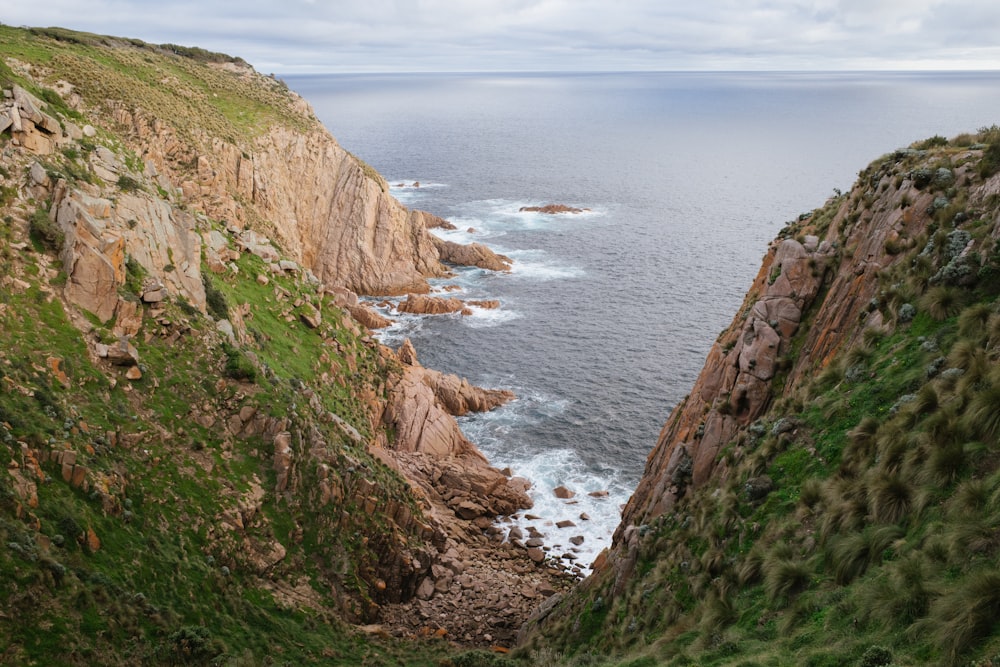 brown and green mountain beside body of water during daytime