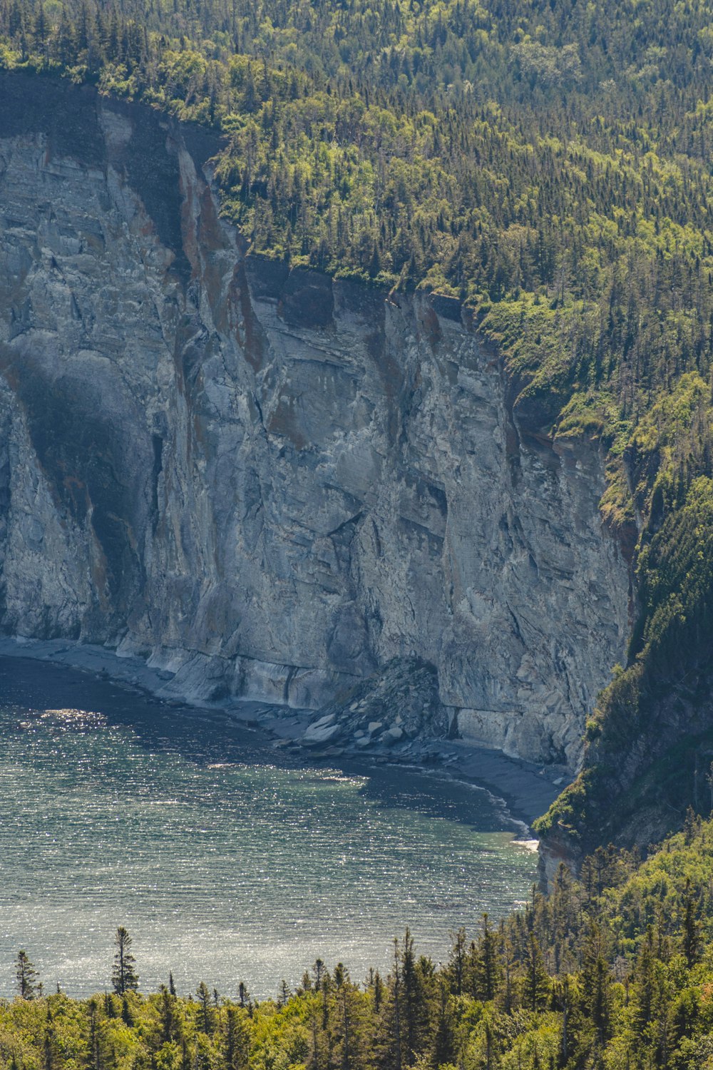 gray rocky mountain beside body of water during daytime