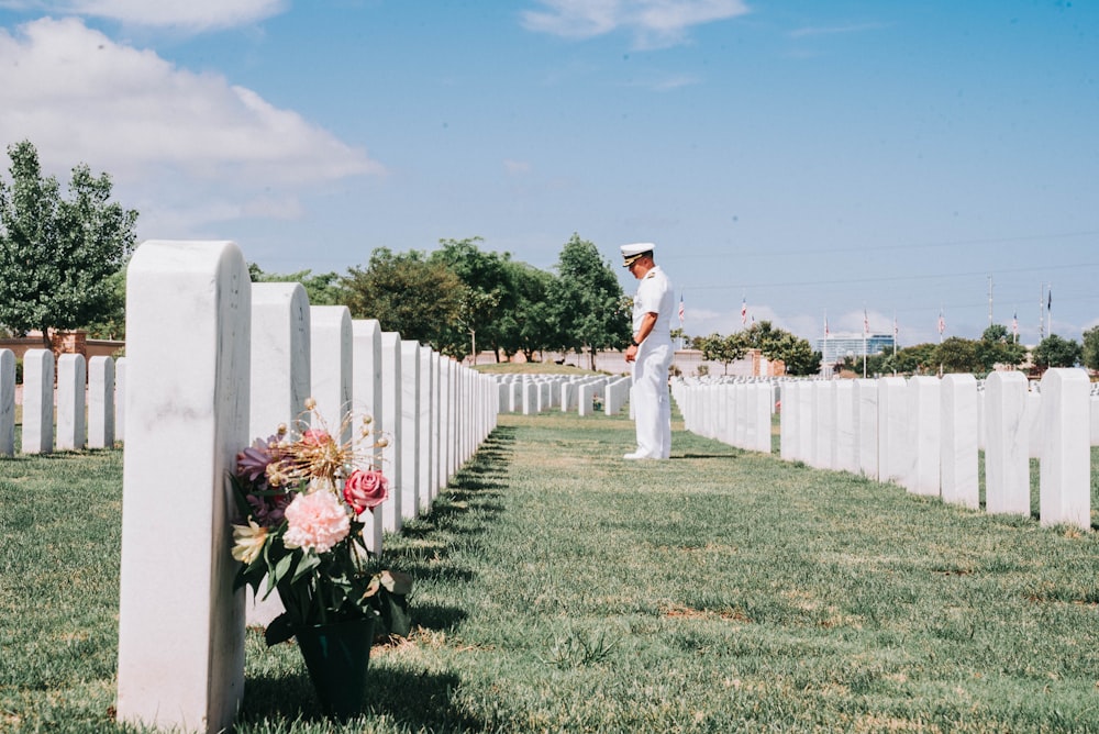 man in white long sleeve shirt and white pants standing on green grass field during daytime