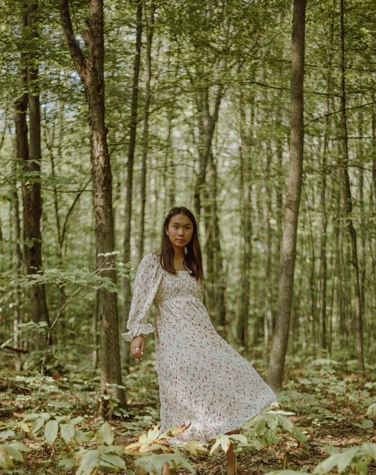 woman in white and black floral dress standing in the woods in Tiny Canada