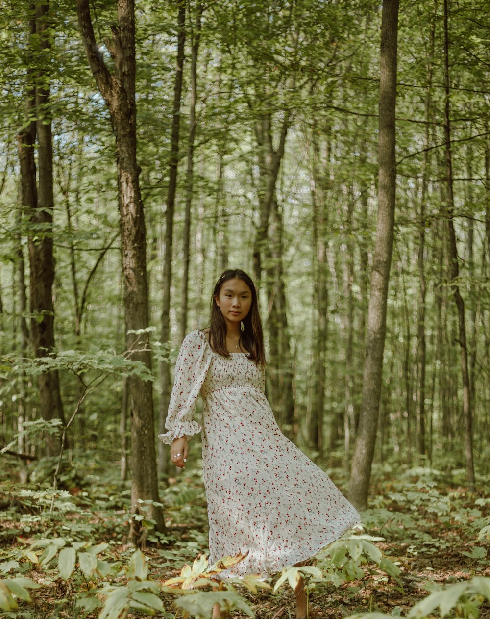 woman in white and black floral dress standing in the woods