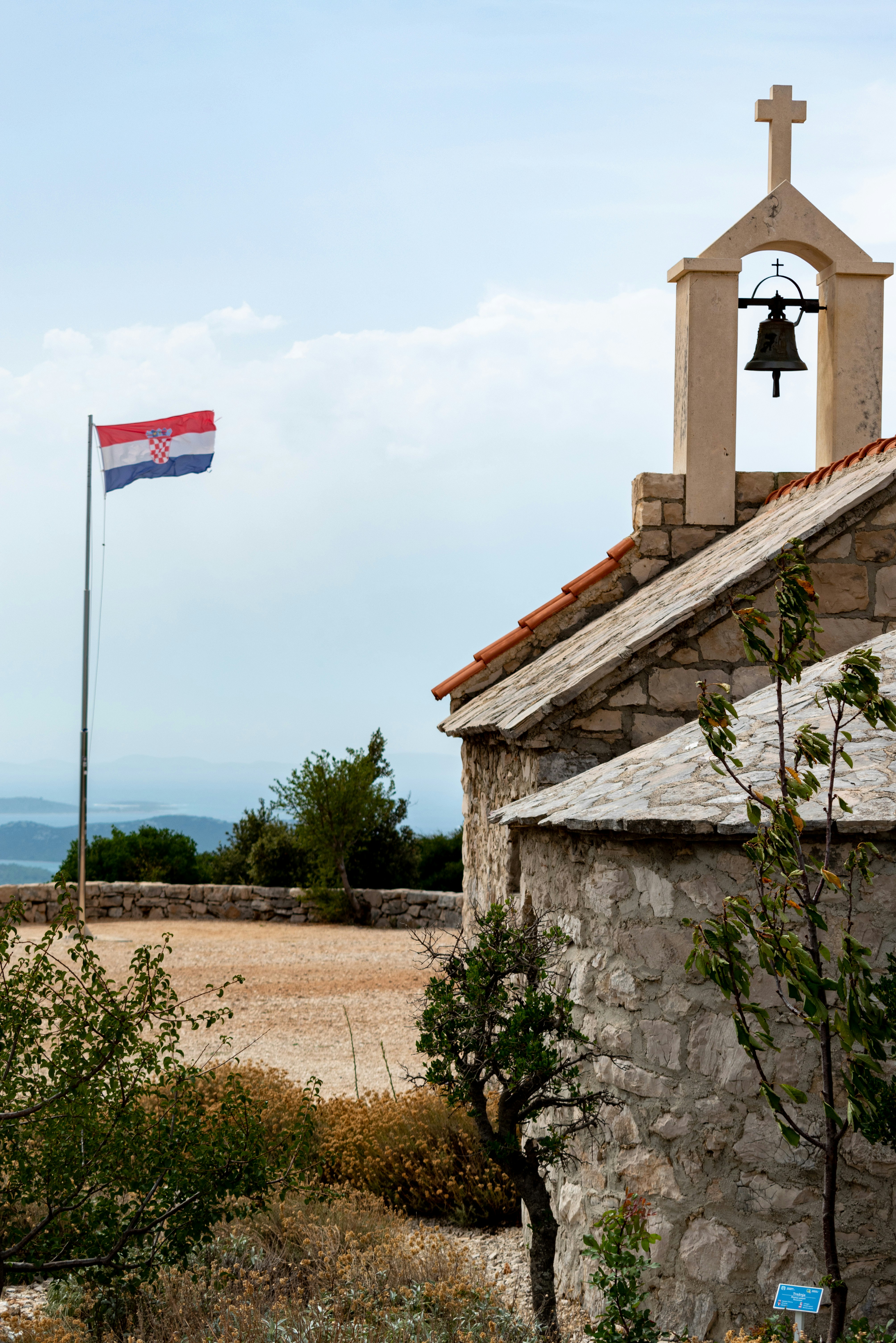 brown and white concrete building with bell flag on top