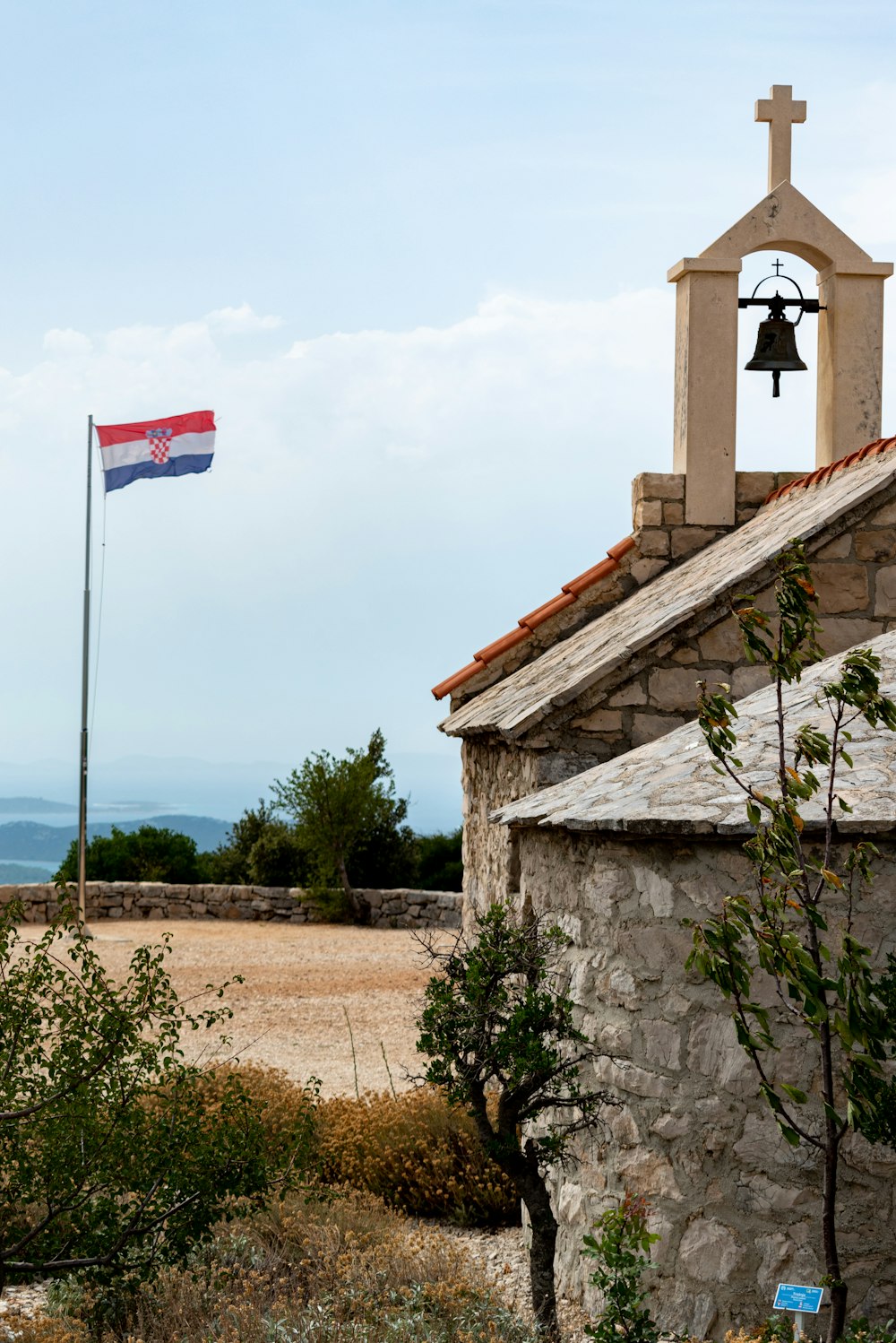 brown and white concrete building with bell flag on top