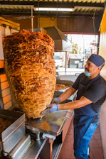 Close-up of sizzling pastor tacos cooking on a vertical spit with vibrant spices.