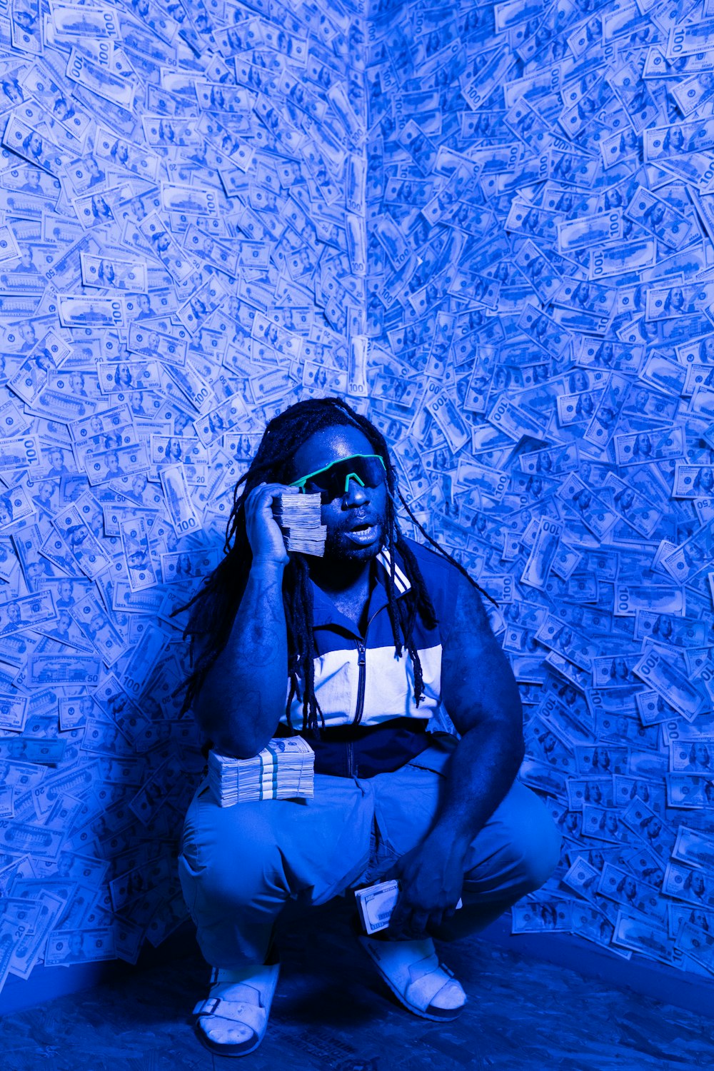 man in black sunglasses and blue denim shorts leaning on blue wall