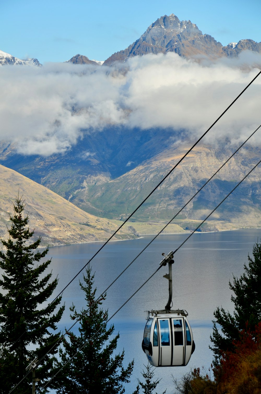 white and black boat on body of water near green trees and mountain during daytime