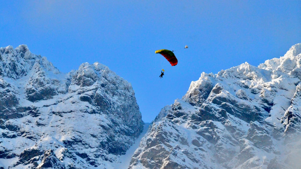 person in yellow parachute over snow covered mountain during daytime