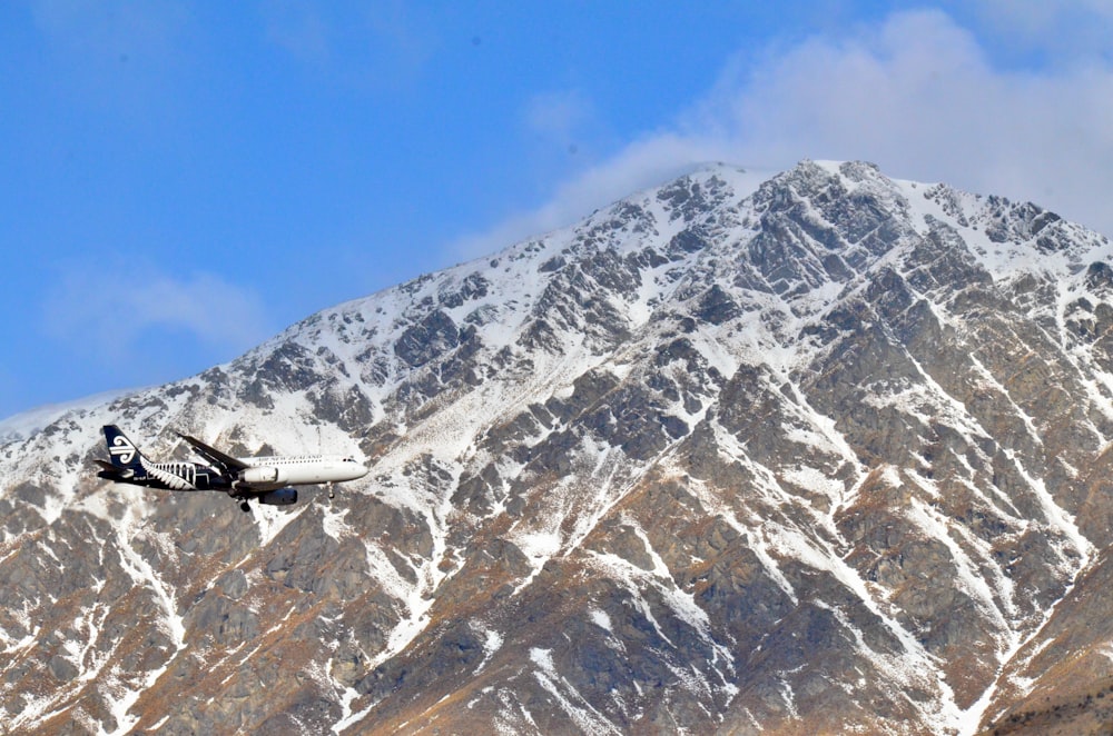 black and white helicopter flying over snow covered mountain during daytime