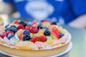 A colorful spread of fresh fruit tarts with green kiwi slices and bright berries.